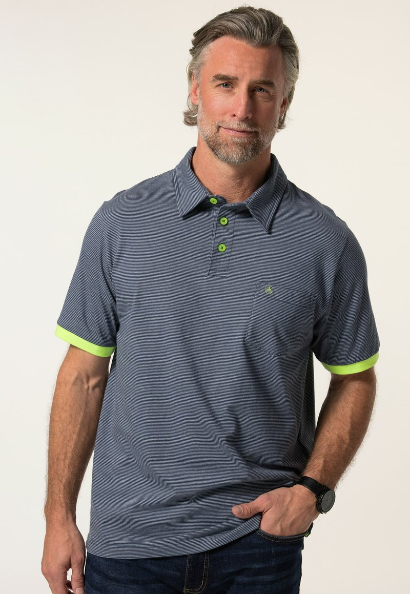 Marinblå randig polo med korta ärmar, limegröna detaljer på ärmarna och kragen samt en bröstficka. Tillverkad av ett mjukt, texturerat material.