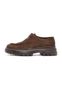 Chaussure en daim marron à lacets avec une semelle épaisse et robuste et des coutures contrastantes le long des orteils et des côtés, vue de côté sur fond blanc.