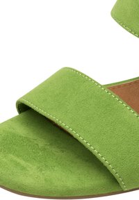 Sandalo in suede verde caratterizzato da due ampie cinghie e solette marroni a contrasto, con cuciture bianche lungo i bordi per un tocco di dettaglio in più.