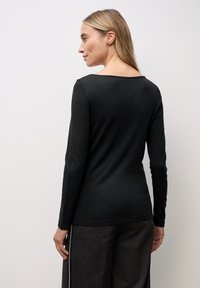 Schwarzes Langarmoberteil mit Bootsausschnitt, aus weichem Stoff gefertigt, mit einer figurbetonten Silhouette und glatter Textur. Keine auffälligen Details.
