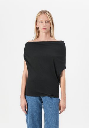 Svart av-skuldra topp laget av et glatt, lett stoff, med en løs design og korte ermer, kombinert med blå vide jeans.