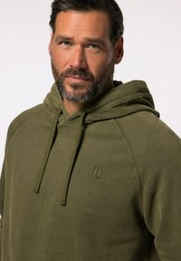 Sudadera con capucha color verde oliva y bolsillo canguro. Presenta un sutil logo bordado. Tejido suave y texturizado con un corte holgado.