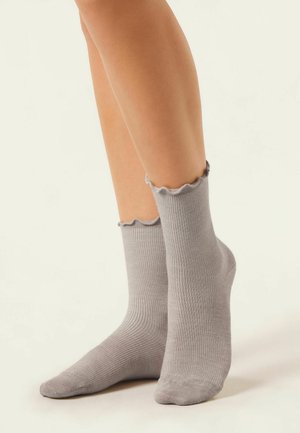 Chaussettes grises côtelées pour la cheville avec un bord festonné, fabriquées en matériau doux, offrant un ajustement confortable et une texture lisse.