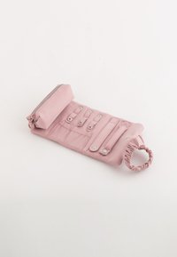 Rosa tygplånbok med ett zippered fack, tryckknapplås och elastisk loophandtag. Har en quiltad textur och metalldetaljer.