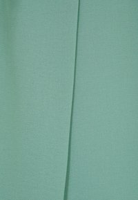 Tessuto di un turchese chiaro con una consistenza liscia, caratterizzato da un sottile motivo di tessitura. Due sezioni si sovrappongono, creando profondità e interesse.