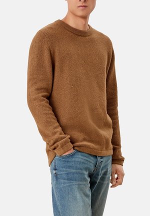 Brun texturerad tröja med rundad halsringning, avslappnad passform och långa ärmar. Bärs med blå jeans och har en avslappnad, vardaglig stil.