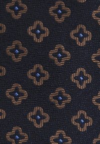 Textil cu un fundal bleumarin, având un model repetitiv de forme florale intercalate în nuanțe de maro și auriu, cu mici diamante albastre în centrul acestora.