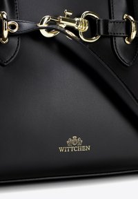 Borsa a mano in pelle nera con hardware dorato, texture liscia e logo in rilievo dorato sul davanti. Include manici doppi.