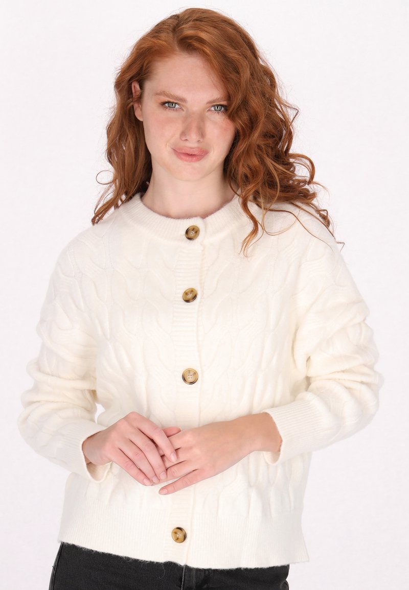 Gebreide crèmekleurige cardigan met een gestructureerd kabelpatroon, voorzien van vijf bruine knopen en ribgebreide manchetten en onderkant.