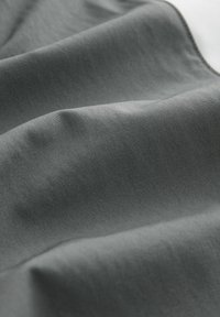 Gray fabric with a smooth texture, showcasing soft folds and subtle variations in shade, indicating a lightweight and flexible material.