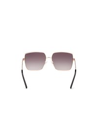 Occhiali da sole quadrati con montatura in metallo color oro rosa, lenti grigie sfumate e punte delle stanghette nere. Presentano un design sottile e minimalista.