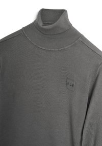 Maglione grigio a collo alto realizzato in morbido tessuto a maglia; presenta un colletto a coste e una piccola toppa con il logo del marchio sul petto.