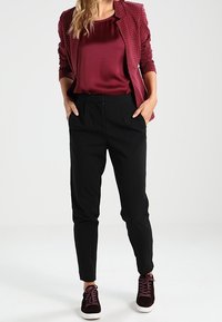 Burgundowy, teksturowany blazer w kropki, zestawiony z jednolitą, burgundową satynową bluzką, czarnymi dopasowanymi spodniami i burgundowymi trampkami.