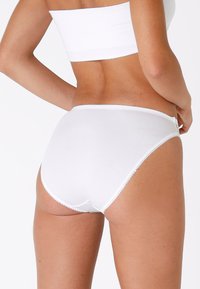 Slip di cotone bianco con una texture liscia, caratterizzati da un alto punto vita e bordi scallop. Design semplice e senza cuciture per il massimo comfort.