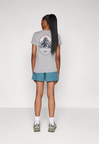 Gray cotton t-shirt featuring a mountain graphic on the back, paired with teal shorts and gray athletic shoes. White socks visible.