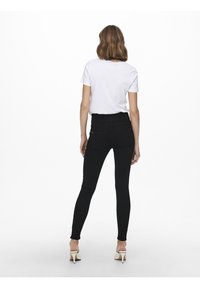 Jeans negros de cintura alta con un corte ajustado, combinados con una camiseta de manga corta blanca. Textura suave con detalles de costura de denim estándar.