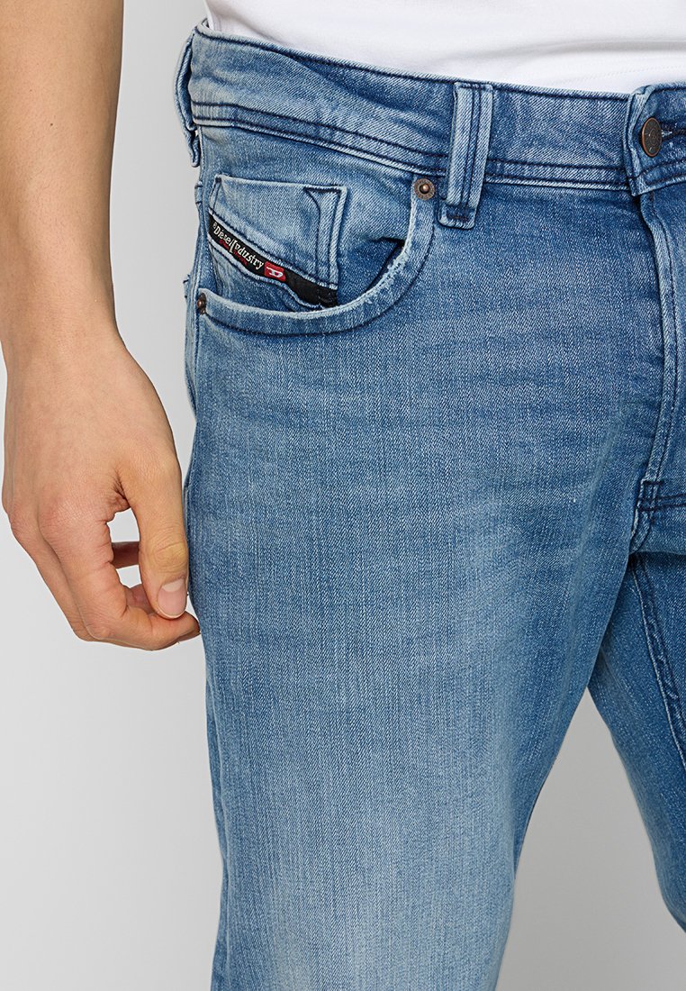 Hellblaue Denim-Jeans im geraden Schnitt, mit einer vorderen Tasche, die sichtbare Nähte aufweist, und einem Markentab innen.