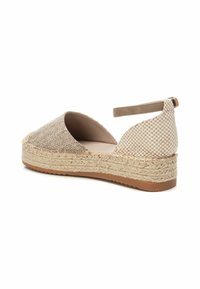 Parte superior de tela tejida en beige con un patrón a cuadros, media suela de yute estilo alpargata y suela exterior de goma marrón. Correa ajustable en el tobillo.
