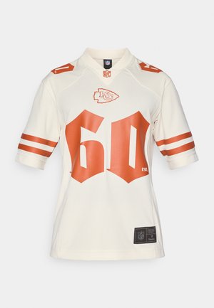 Beige NFL-Trikot mit roten Streifen an den Ärmeln und der großen "60" in Rot auf der Vorderseite, einschließlich Teamlogo und Etiketten am Saum.