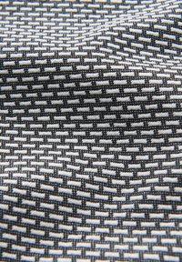 Textile featuring a woven pattern with alternating black and white threads, creating a textured, grid-like appearance.