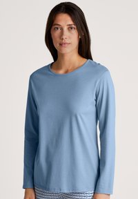 Lichtblauw langdziende shirt met een ronde halslijn, gemaakt van zachte stof, met een gladde textuur en een relaxte fit. Geen patronen of accenten.