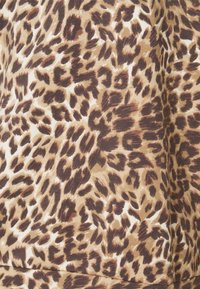 Tela de estampado de leopardo que presenta una mezcla de tonos marrón claro, crema y marrón con un patrón texturizado variado. Material suave y ligero.