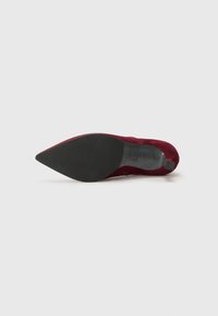 Escarpin en nubuck bordeaux avec un bout pointu, une semelle noire et un dessus texturé. Dispose d'un petit talon pour une élévation supplémentaire.