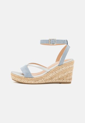 Sandale compensée en daim bleu clair avec boucle de bride à la cheville, brides croisées blanches et semelle plateforme en jute tressée.