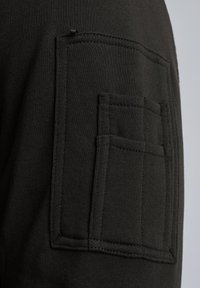 Czarna bawełniana dzianina na sweatshirt z dużą kieszenią naszywaną o prostokątnym kształcie. Miękka tekstura i widoczne akcenty stębnowania.