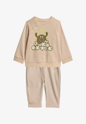Beiger Jogginganzug für Kleinkinder mit langärmligem Oberteil mit einem Cartoon-Monster, Fußballbällen, die "ADIDAS" buchstabieren, und passenden Hosen mit Logo.