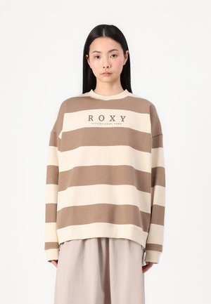 Hnedo-krémový pruhovaný sveter s okrúhlym výstrihom a voľným strihom. Na prednej strane sa nachádza text "ROXY ZALOŽENÉ 1990".
