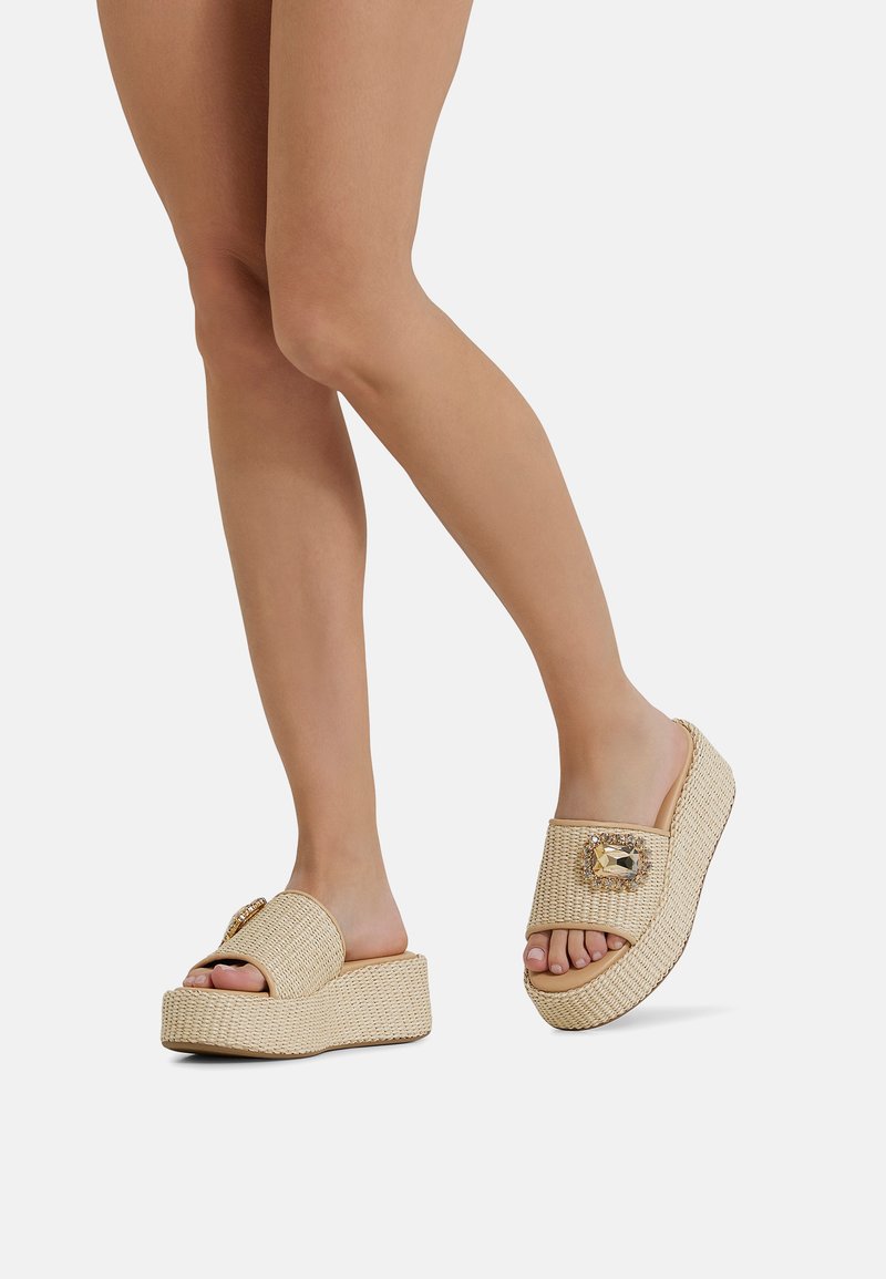 Sandali piattaforma intrecciati beige con un accento decorativo di gioiello sulla cinghia e una suola in sughero testurizzata per una migliore aderenza.