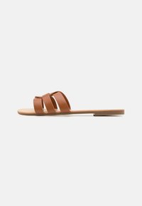 Hnědé ploché sandály s třemi širokými pásky, plochou podešví a hladkým koženkovým vzhledem. Minimalistický design, otevřená špička a zadní část.