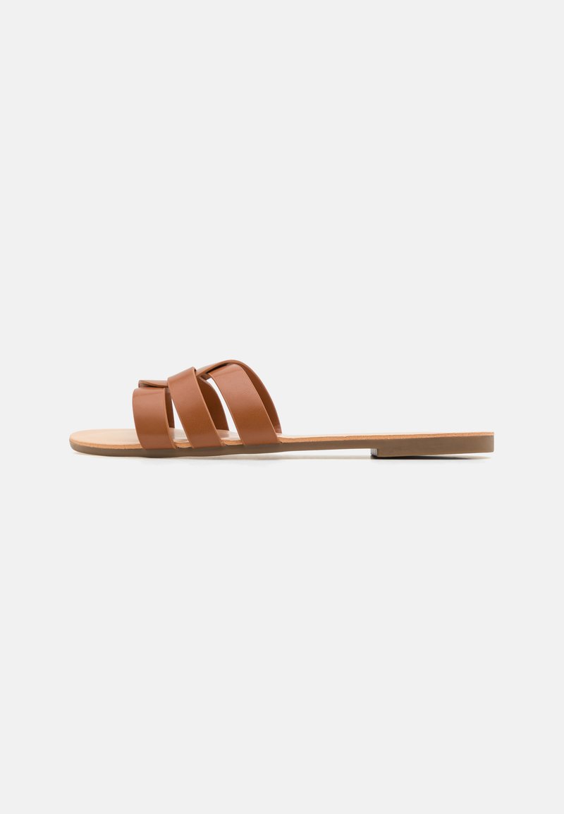 Hnědé ploché sandály s třemi širokými pásky, plochou podešví a hladkým koženkovým vzhledem. Minimalistický design, otevřená špička a zadní část.
