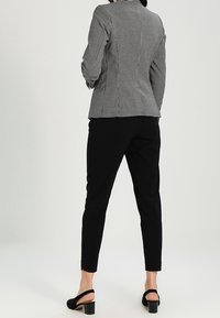 Svart och vit rutigt kavaj med en skräddarsydd passform, kombinerad med svarta avsmalnande byxor och svarta öppetåiga klacksandaler.