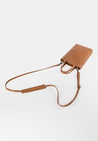 Taschentasche aus braunem Leder mit rechteckiger Form, doppelten Griffen oben und einem abnehmbaren Schulterriemen. Glatte Textur mit minimalem Zubehör.