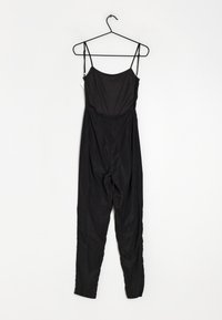 Svart jumpsuit med tunna axelremmar, en figursydd överdel och lösa, avsmalnande ben. Tillverkad av ett mjukt, lätt material. Dold dragkedja i ryggen.