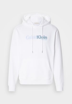 Sweatshirt à capuche blanc en tissu doux, doté d'une poche avant, d'un cordon de serrage et d'un logo "Calvin Klein New York" en bleu clair.