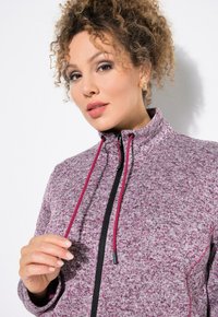 Fleece zip-up jakke i en blanding af bordeaux og grå, med høj krave, snore og en sort lynlås for kontrast. Blød tekstur.