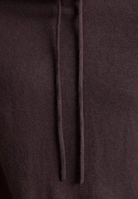 Brun hoodiefabric med en mjuk textur och två klädband vid halsringningen. Ytan är jämn med en något ludden utseende.