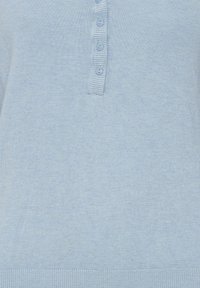 Pull en tricot bleu clair avec un col henley, cinq boutons assortis, et des bords côtelés aux ourlets et aux poignets. Texture douce partout.