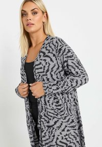 Lungo cardigan grigio con motivo astratto nero, realizzato in tessuto morbido; presenta un'apertura frontale, maniche lunghe e vestibilità comoda.