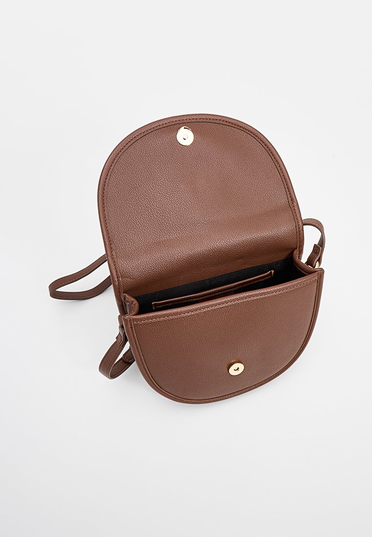 Bolso cruzado de imitacion cuero marrón con tapa redondeada, cierre a presión dorado, correa ajustable y un interior negro que cuenta con ranuras para tarjetas.