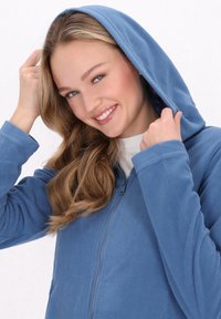 Felpa blu in pile con zip frontale e un ampio cappuccio. Presenta una texture morbida e maniche lunghe, progettata per comfort e calore.