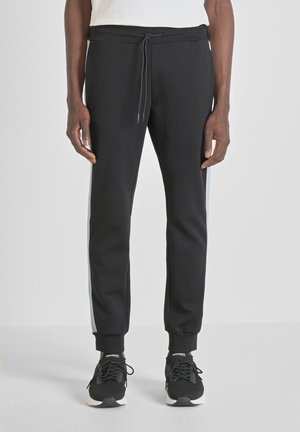 Zwarte sportieve joggers met een drawstring taille, taps toelopende benen, zijstrepen in lichtblauw en geribbelde manchetten, gecombineerd met zwarte sneakers.