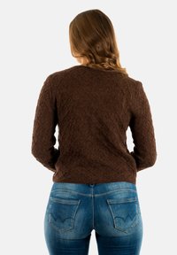 Bruine gebreide trui met ruitpatroon, gecombineerd met lichtblauwe jeans met gestikte achterzakken. Gezien van achteren.