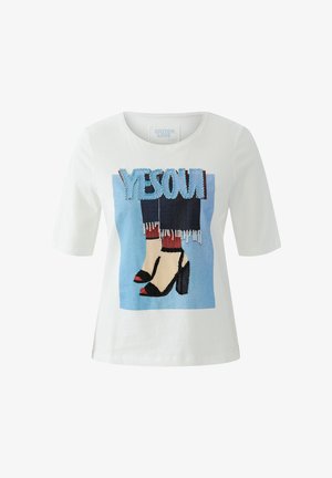 Chemise blanche à manches courtes avec un graphique de jambes en chaussettes rouges et talons noirs, fond bleu, et texte bleu "YES OK" au-dessus.