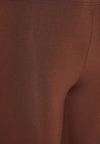 Bruine legging gemaakt van zachte, rekbare stof, met een gladde textuur en een strakke pasvorm met een elastische tailleband.