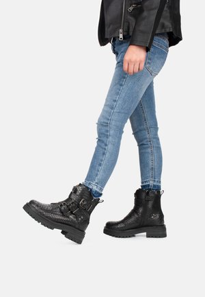 Zwarte enkellaarzen van gestructureerd leer, met gespdetails en een stevige zool, gecombineerd met slim-fit blauwe jeans.