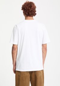 T-shirt en coton blanc à manches courtes et décolleté rond, vu de l'arrière. Le tissu semble doux avec une texture lisse.